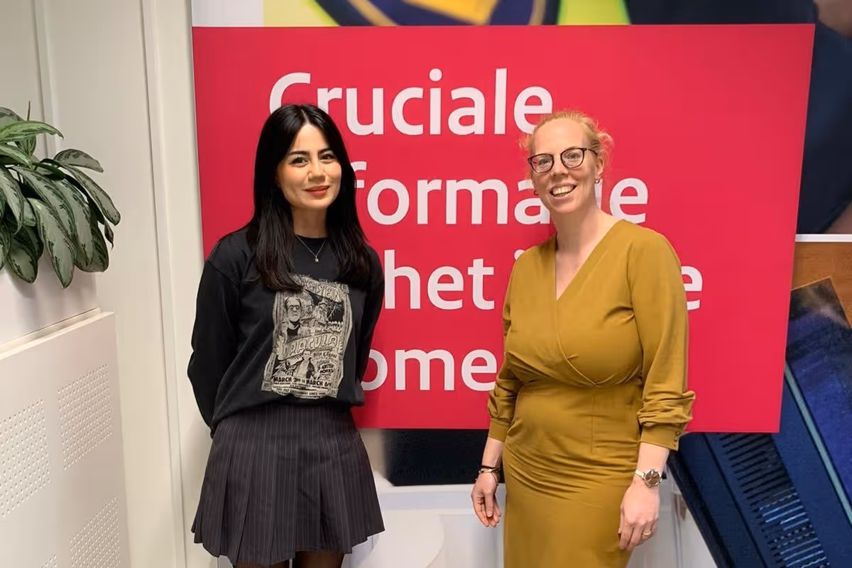 Boshra Bassam en Marina Zoet staan voor een gedecoreerde wand