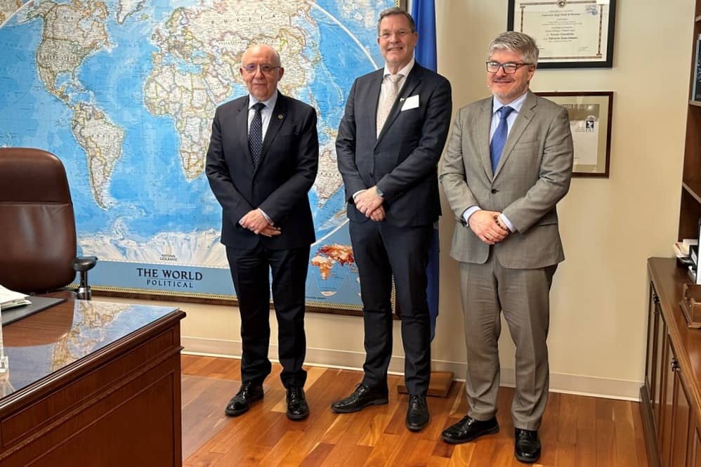 Cor de Jonge samen met twee andere personen in een kantoor staand voor een grote wereldkaart