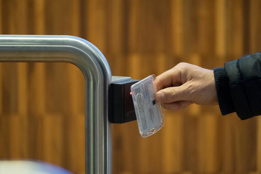 Een hand van een persoon houdt een toegangspasje voor een elektronische kaartlezer