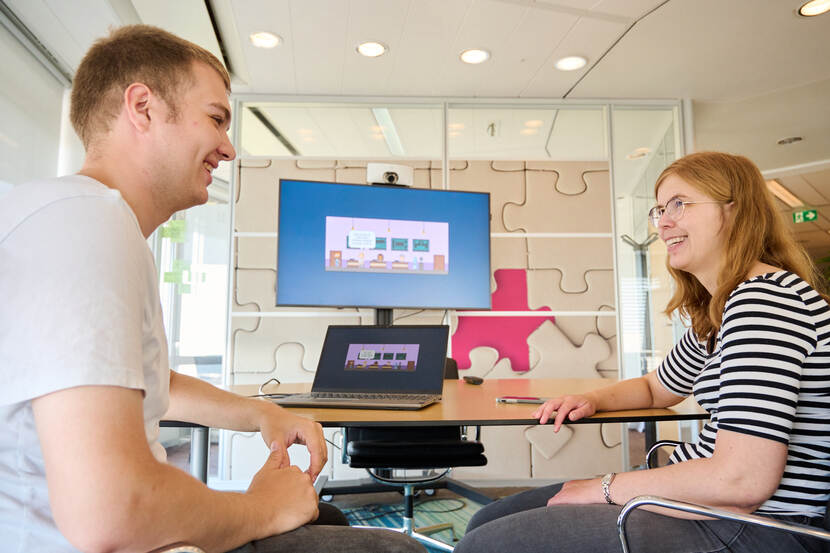 Twee Justid-medewerkers samen zittend bij een computerscherm