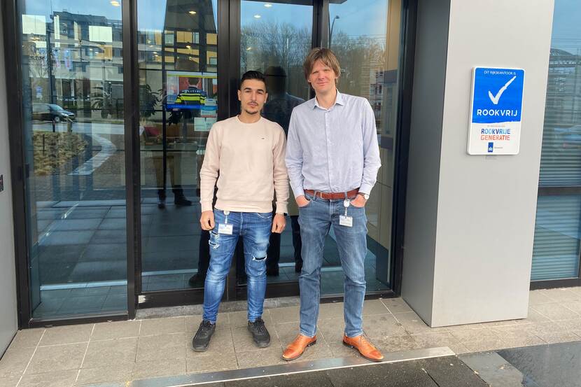 Emin en Tim voor de deur van het pand van de Justitiële Informatiedienst