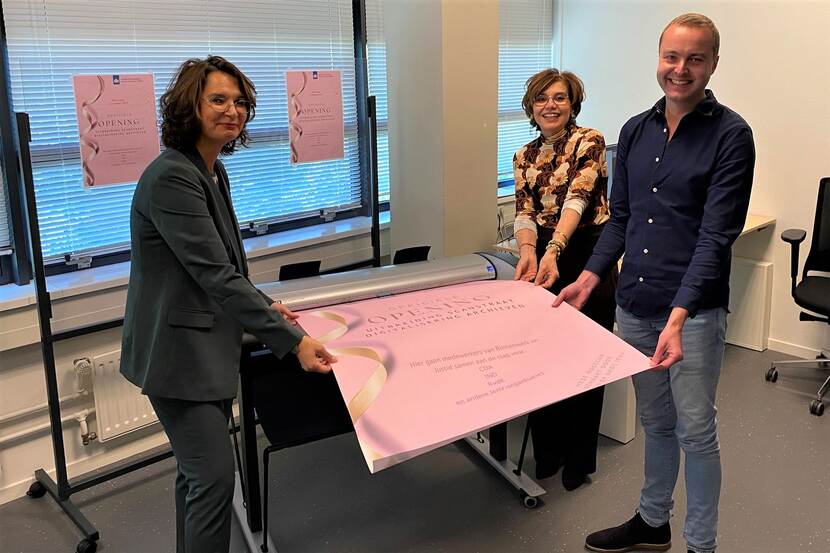Drie mensen scannen een grote poster in als officiële handeling