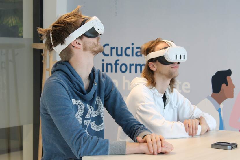 Twee mensen aan tafel met een VR-bril op