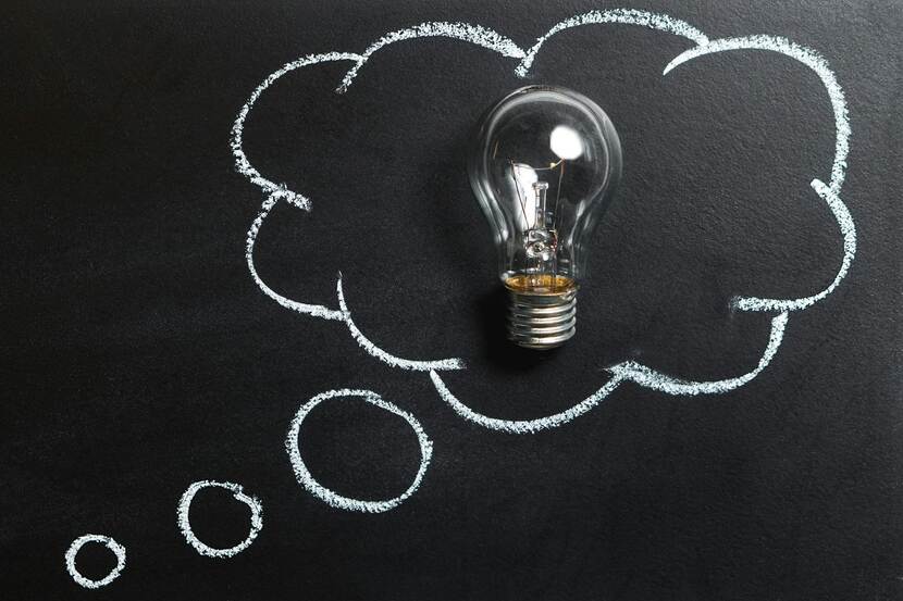Een gloeilamp ligt op een schoolbord in een krijttekening van een denkballon